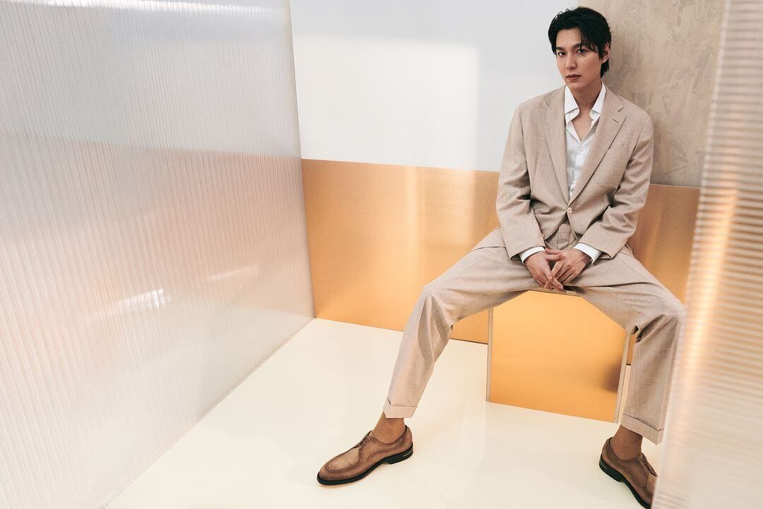 Model seated on a chair wearing a tailored light suit
