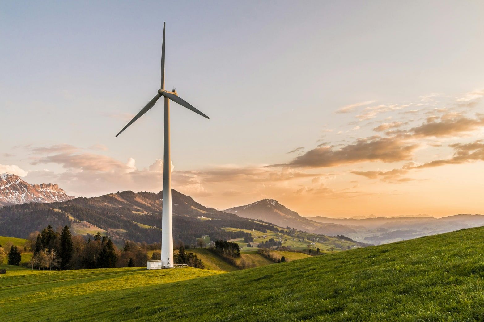 Wind turbine on a green hillside at sunset